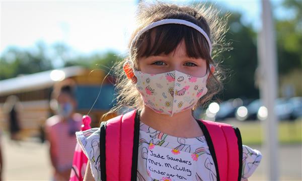 girl smiles while wearing mask